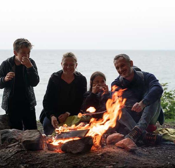 Family sitting around a campfire with sea views at Staksrode Forest
