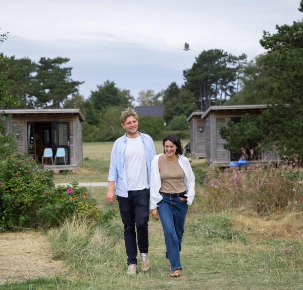 Couple waling towards the beach in front om cabin at Tunø Campsite in the Coastal Land in Denmark