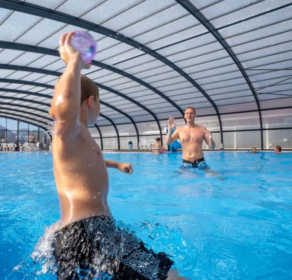 A boy and a father playing ball in a pool at Horsens City Camping near Husodde in Destination Coastal Land