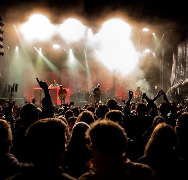 Hands in the air in front of a stage in the evening at the wall of sound in Destination Coastal Land