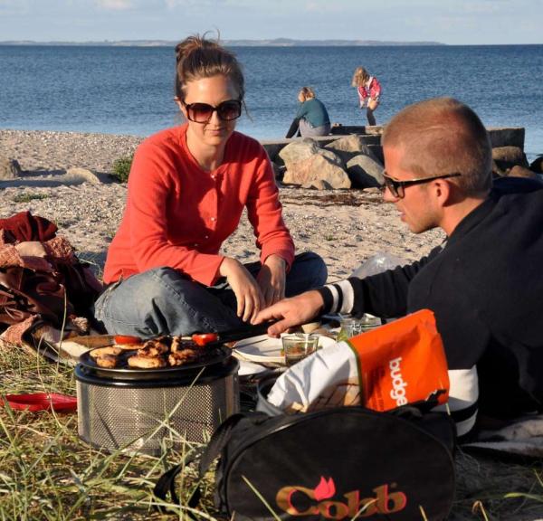 Family having fun and barbecuing by the beach at Ajstrup Camping - part of Destination Coastal Land