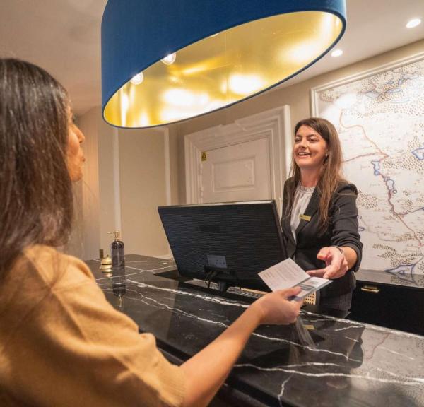 Woman checking into Jørgensens Hotel while the receptionist hands her key card