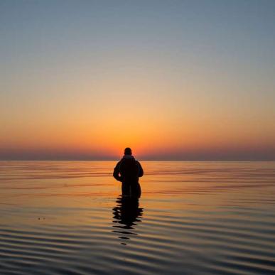 Man fishing in the sea at sunrise