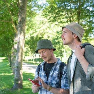 Two men with bucket hats looking out into the countryside with green trees in the background in the Destination Coastal Land