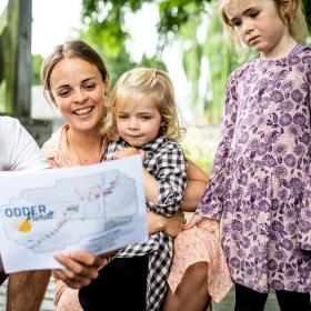 Family standing with at treasure map from the treasure hunt Odder rundt