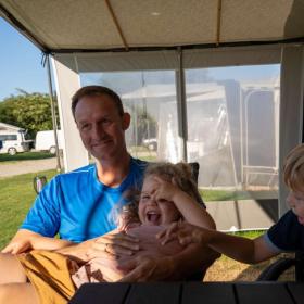Father with two children in an awning by a caravan at Horsens City Camping - part of Destination Coastal Land