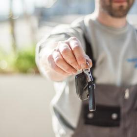 A man holding out car keys at car hire company