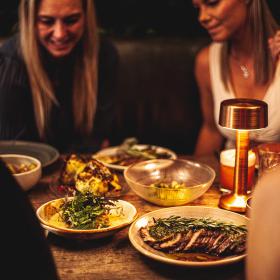 Kvinder sidder ved et bord med mad på Gran Social i Horsens' Latinerkvarter 