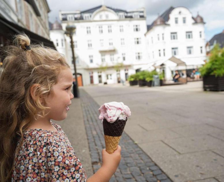 A girl holding an ice cream in front of Centralhotellet in Odder