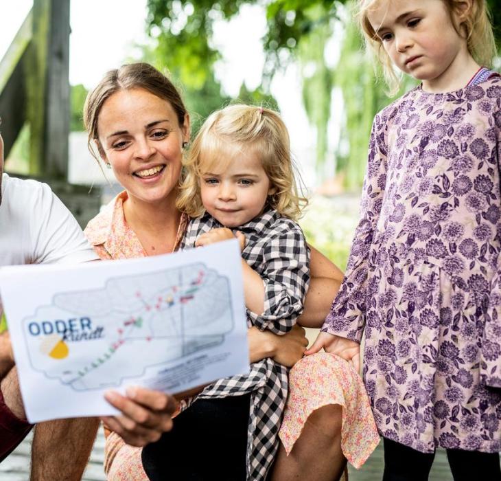 Family standing with at treasure map from the treasure hunt Odder rundt
